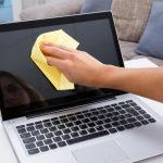 Mujer limpiando computadora portátil