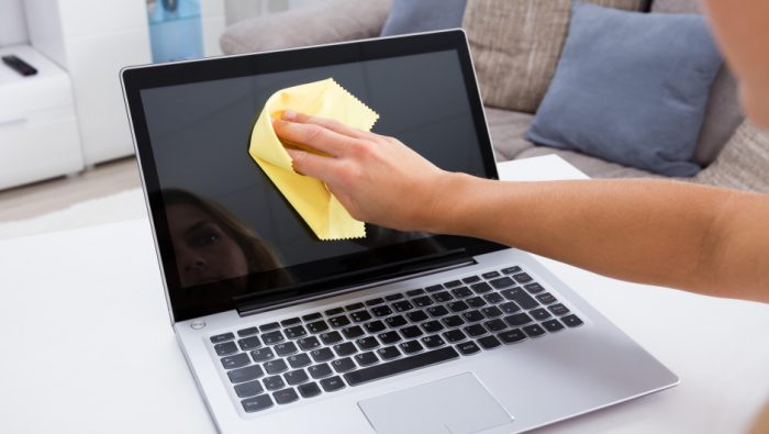 Mujer limpiando computadora portátil
