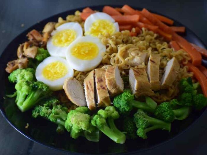 Plato con pollo a la plancha, huevos cocidos, brócoli y zanahoria que muestra una comida rica en proteína accesible y vegetales.