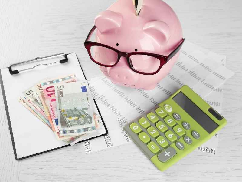 Alcancía con billetes, recibos y una calculadora, representando ahorro y control del presupuesto.