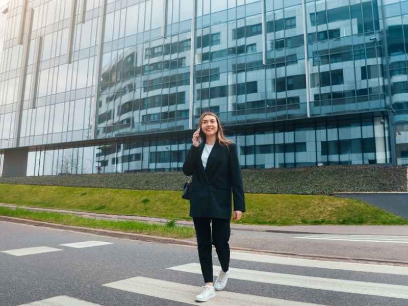 Mujer caminando frente a edificio moderno, representando movilidad urbana y acceso peatonal en desarrollos conectados.