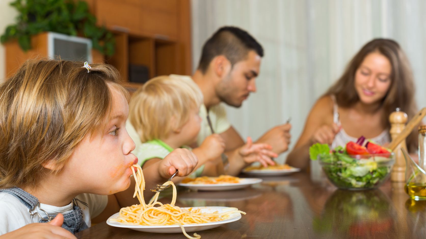 Familia reunida alrededor de una mesa compartiendo diferentes platillos durante una comida en casa.